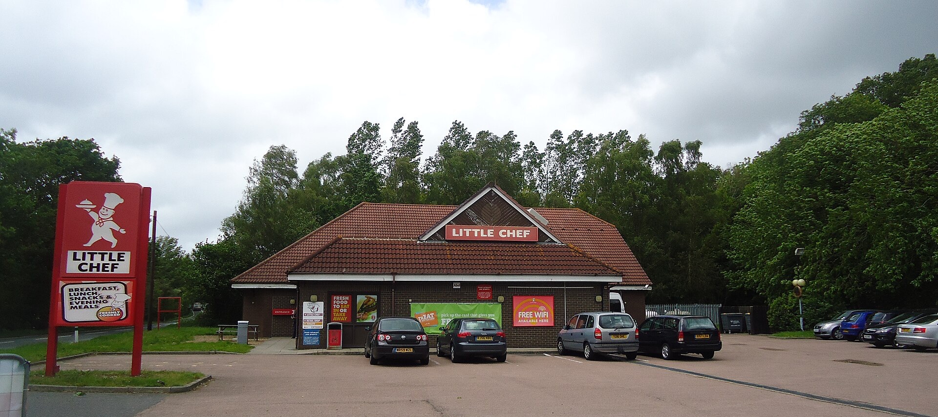 Little Chef roadside restaurant in Flimwell, with its red-and-white chef sign, brick building and parked cars.